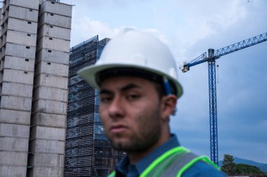 İnşaat işçisi portresi, güneşli bir günde şantiyede.