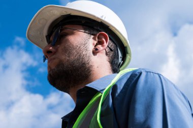 İnşaat işçisi portresi, güneşli bir günde şantiyede.