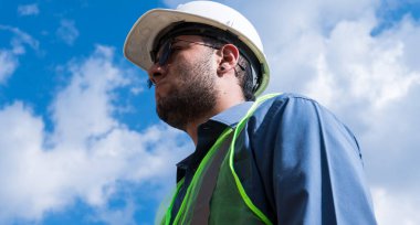 İnşaat işçisi portresi, güneşli bir günde şantiyede.