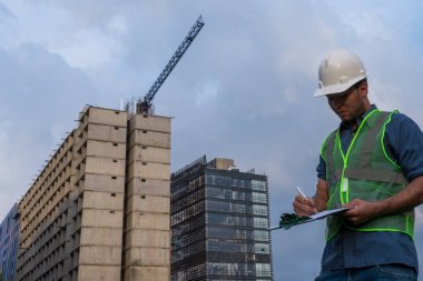  İşçi inşaat sahasında anlaşma için bazı belgeleri imzalıyor.