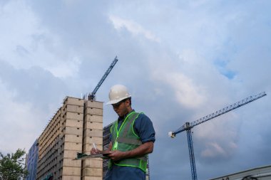  İşçi inşaat sahasında anlaşma için bazı belgeleri imzalıyor.