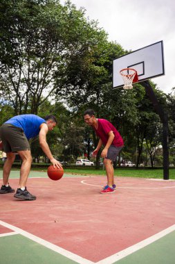 Arkadaşlar yazın güneşli bir günde mahkemede basketbol oynuyorlar. 