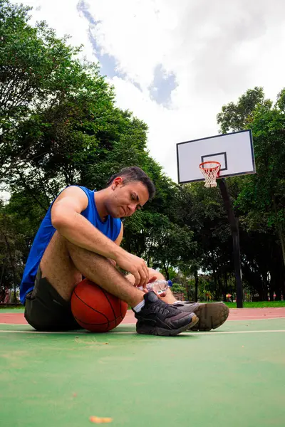 Man taking rest from basketball training  in court in sunny day at summer