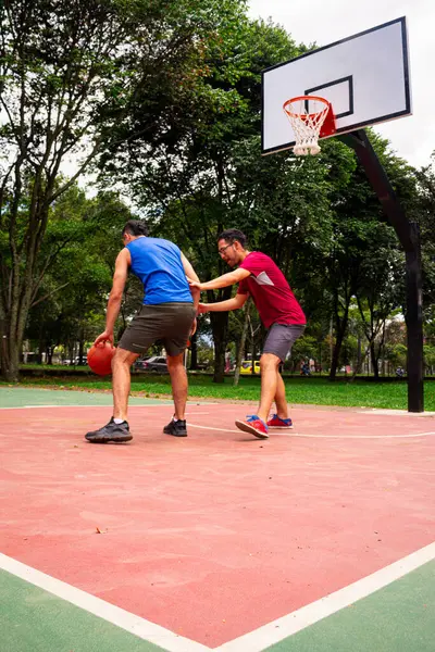 Arkadaşlar yazın güneşli bir günde mahkemede basketbol oynuyorlar. 