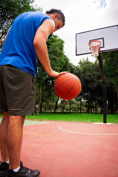 Yazın güneşli bir günde mahkemede basketbol antrenmanı yapan adam. 