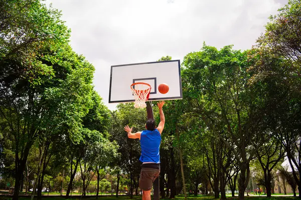 Yazın güneşli bir günde mahkemede basketbol antrenmanı yapan adam. 