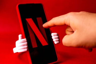 Netflix logosuna sahip akıllı telefon ekranda ve kırmızı arkaplanda