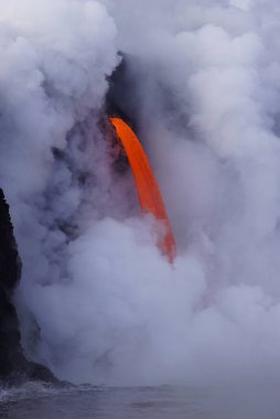 Hot  Lava stream flowing out of cliff into the ocean surrounded by white steam cloud