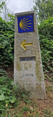 Santiago de Compostela 'ya giden yolu gösteren sarı deniz tarağı kabuğu ve okla mil taşı işareti.