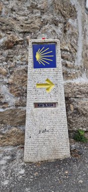 Santiago de Compostela 'ya giden yolu gösteren sarı deniz tarağı kabuğu ve okla mil taşı işareti.