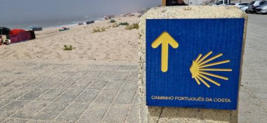 Sarı deniz tarağı kabuğu ve ok işareti Santiago de Compostela 'ya giden yolu gösteriyor.
