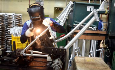 Sidoarjo, Indonesia - April 9, 2015: worker welding material the spare part on the assembly line at bicycle assembly from Indonesia Polygon in Sidoarjo, East Java, Indonesia