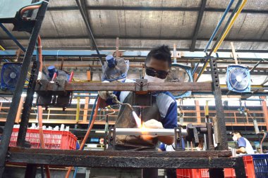 Sidoarjo, Indonesia - April 9, 2015: worker welding material the spare part on the assembly line at bicycle assembly from Indonesia Polygon in Sidoarjo, East Java, Indonesia