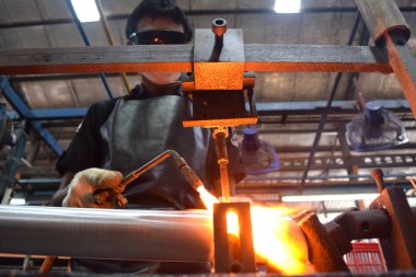 Sidoarjo, Indonesia - April 9, 2015: worker welding material the spare part on the assembly line at bicycle assembly from Indonesia Polygon in Sidoarjo, East Java, Indonesia