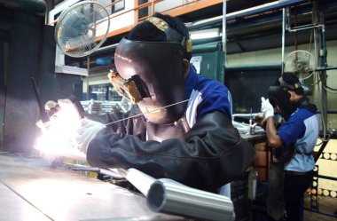 Sidoarjo, Indonesia - April 9, 2015: worker welding material the spare part on the assembly line at bicycle assembly from Indonesia Polygon in Sidoarjo, East Java, Indonesia