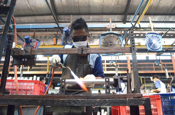 Sidoarjo, Indonesia - April 9, 2015: worker welding material the spare part on the assembly line at bicycle assembly from Indonesia Polygon in Sidoarjo, East Java, Indonesia