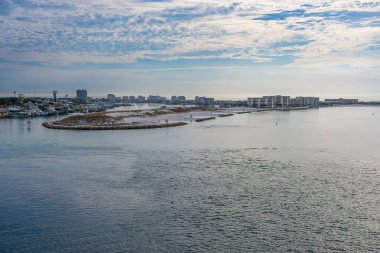 Destin Harbor Florida ABD, parlak mavi bir gökyüzünün altında zümrüt yeşili sulara yansıyan kabarık bulutlarla mükemmel bir sahil sahnesi yaratıyor..