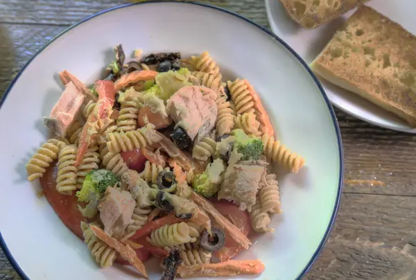 Top view of salmon pasta salad on natural wood surface