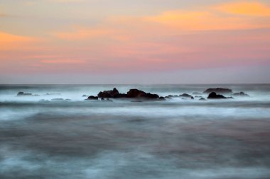 San Simeon, California yakınlarında gün batımında dalgalar kıyı şeridi boyunca çarpışıyor..