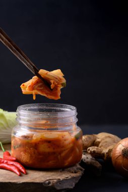 Kasede kimchi lahanası, siyah arka planda yemek çubukları, Asya mayalanmış yemekleri.