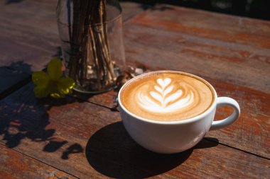 Tahta masada kahve fincanı şeklinde kalp ağacı şeklinde Latte sanat kahvesi, sıcak içecek.