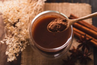 Tarçın çubuklu sıcak kakao, yıldız anason ve kaşık kakao tozu, kış mevsiminde sıcak içecek.