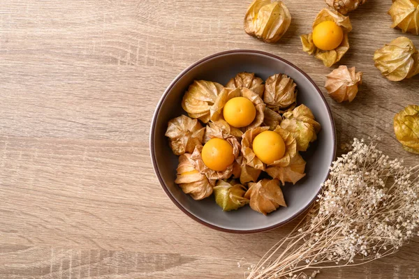 Cape gooseberry or golden berry (Physalis peruviana) in bowl on wooden background with copy space, Table top view