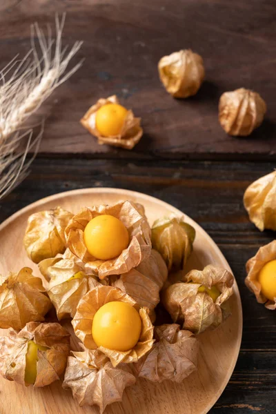 Cape gooseberry or golden berry (Physalis peruviana) on wooden plate