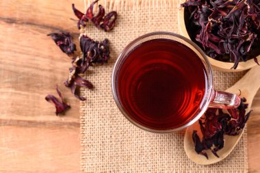 Bardakta Roselle çayı, ahşap arka planda kuru roselle, kan basıncını düşürmek için bitki içeceği.