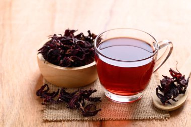 Bardakta Roselle çayı, ahşap arka planda kuru roselle, kan basıncını düşürmek için bitki içeceği.