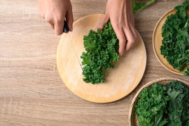 Green Kale or leaf cabbage cutting on wooden board, Healthy vegetable, Table top view