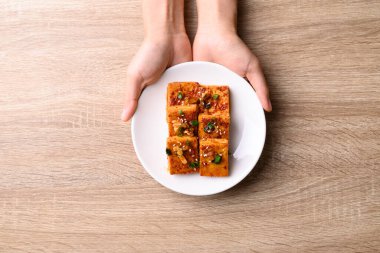 Korean side dish, spicy braised tofu (Dubu Jorim) with hand on wooden background, Table top view