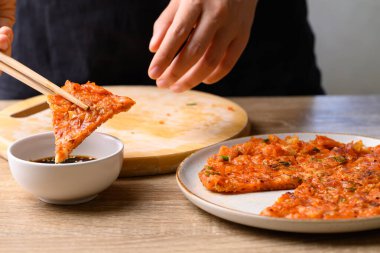 Kimchi pancake (Kimchi jeon or kimchi buchimgae) eating with soy dipping sauce, Korean food