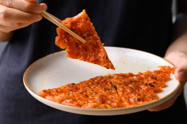Kimchi pancake (Kimchi jeon or kimchi buchimgae) with hand ready to eating, Korean food