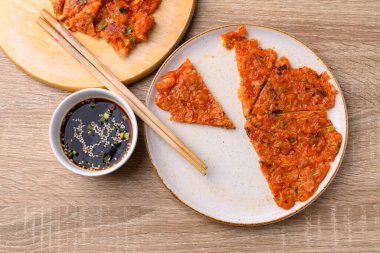 Kimchi pancake (Kimchi jeon or kimchi buchimgae) on plate eating with soy dipping sauce, Korean food, Table top view