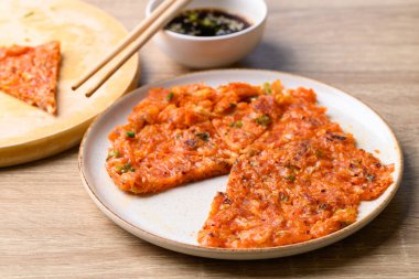 Kimchi pancake (Kimchi jeon or kimchi buchimgae) on plate eating with soy dipping sauce, Korean food