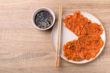 Kimchi pancake (Kimchi jeon or kimchi buchimgae) on plate eating with soy dipping sauce, Korean food, Table top view