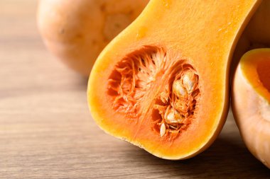 Tahta arka planda yarım tereyağlı ezme, organik sebzeler.