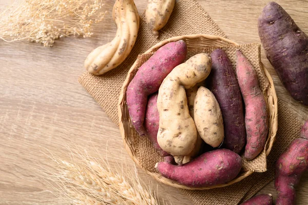 stock image Organic Asian sweet potatoes in basket on wooden background, Table top view