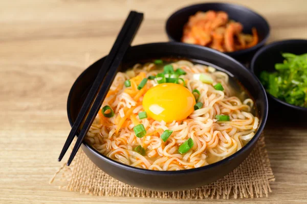 stock image Asian instant noodle soup with fresh egg yolk eating with kimchi cabbage and seaweed salad