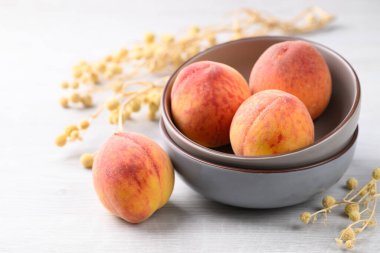 Beyaz masada olgun şeftali meyveleri kasede