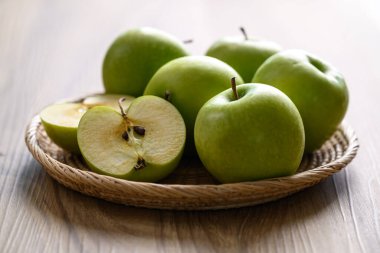 Tahta arka planda sepetteki yeşil elma meyvesi, sağlıklı meyve.