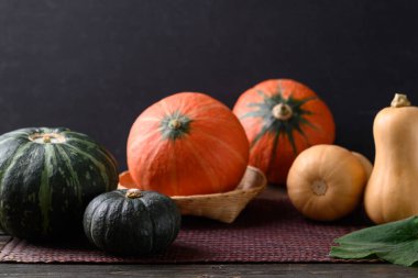 Balkabağı ve tereyağlı kabak siyah arka planlı ahşap masa, sonbahar mevsiminde organik sebze.