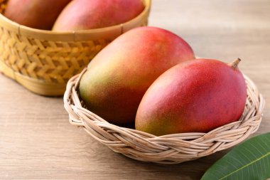 Mango meyvesi (Palmer mango) ahşap arka planda sepette, tropikal meyve