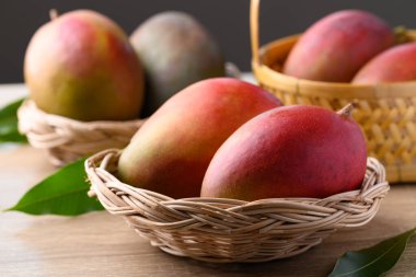 Mango meyvesi (Palmer mango) ahşap arka planda sepette, tropikal meyve