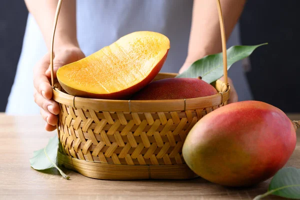 stock image Mango fruit (Palmer mango) in basket with hand on wooden background, Tropical fruit