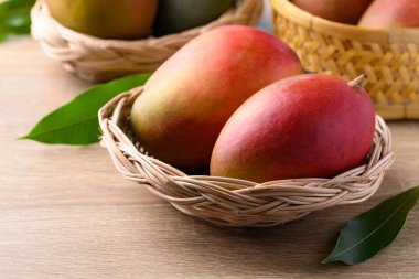 Mango meyvesi (Palmer mango) ahşap arka planda sepette, tropikal meyve