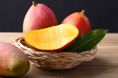 Mango meyvesi (Palmer mango) ahşap arka planda sepette, tropikal meyve