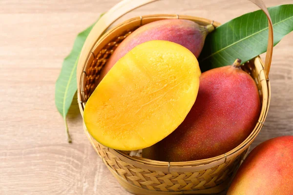 Mango meyvesi (Palmer mango) ahşap arka planda sepette, tropikal meyve