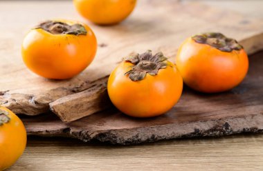 Ahşap arka planda taze hurma meyvesi, mevsimlik sonbahar meyvesi